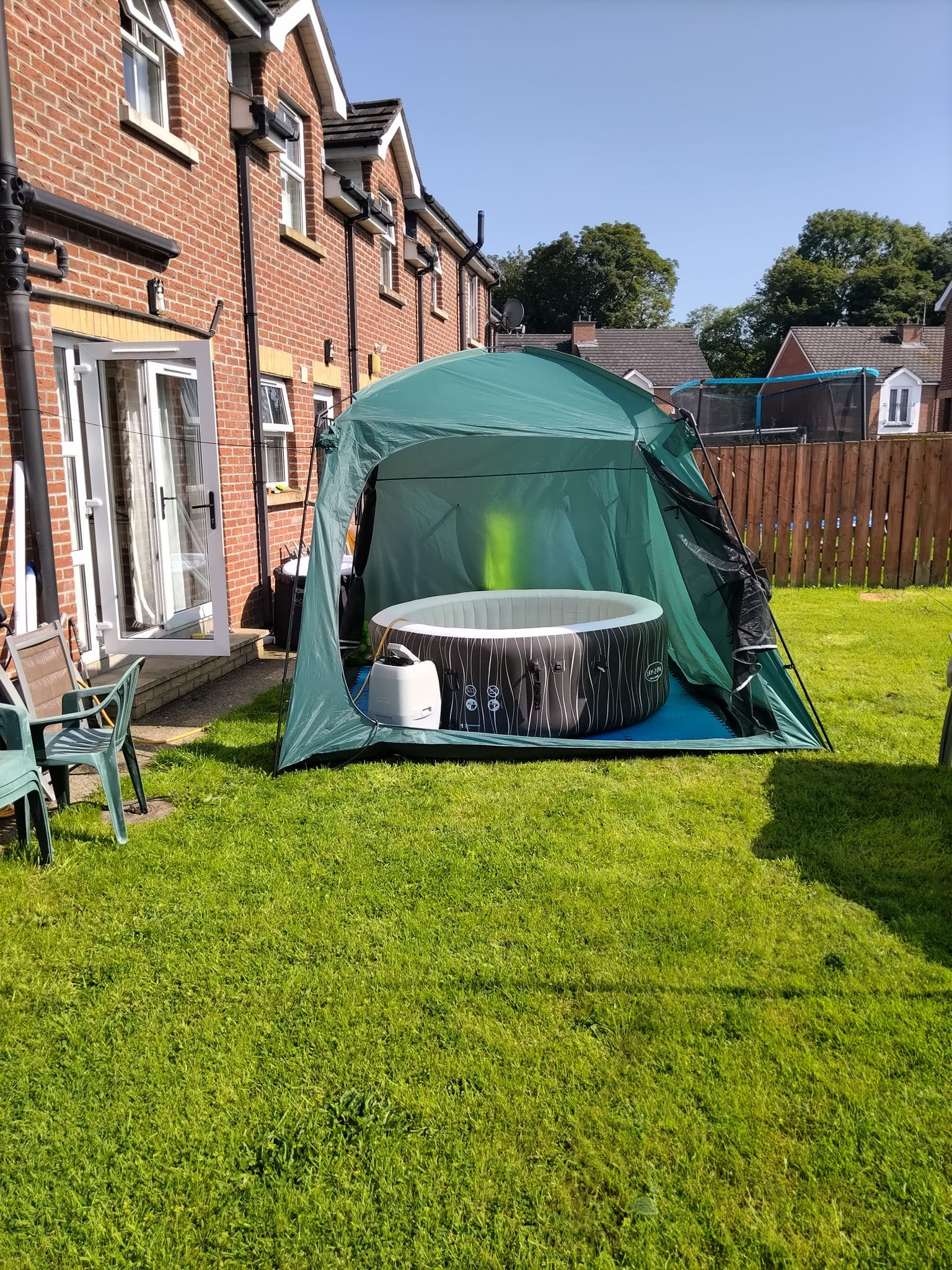 green hot tub with tent in garden sunny day