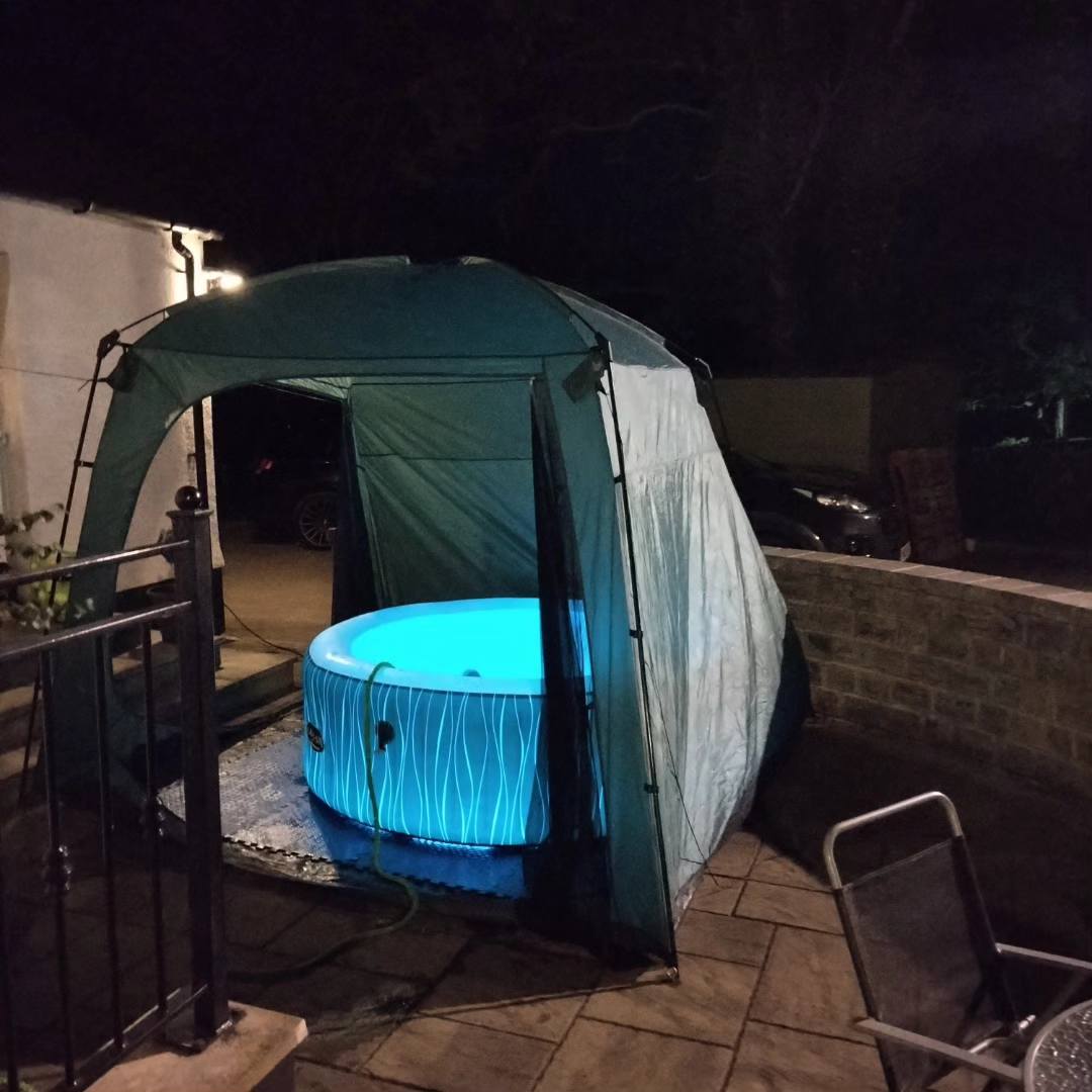 blue lit hot tub with tent and night